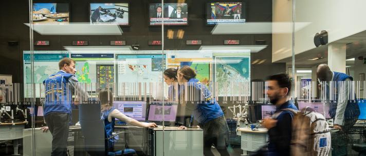 View from the outside of the ERCC control room, a glass wall, a person walking by in front.