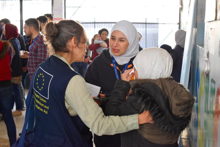Aid worker conforting 2 women.