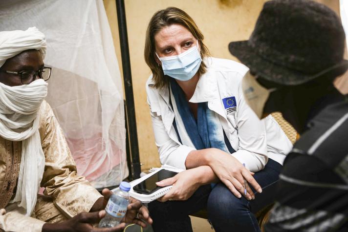 Aid worker talking to people while seated.