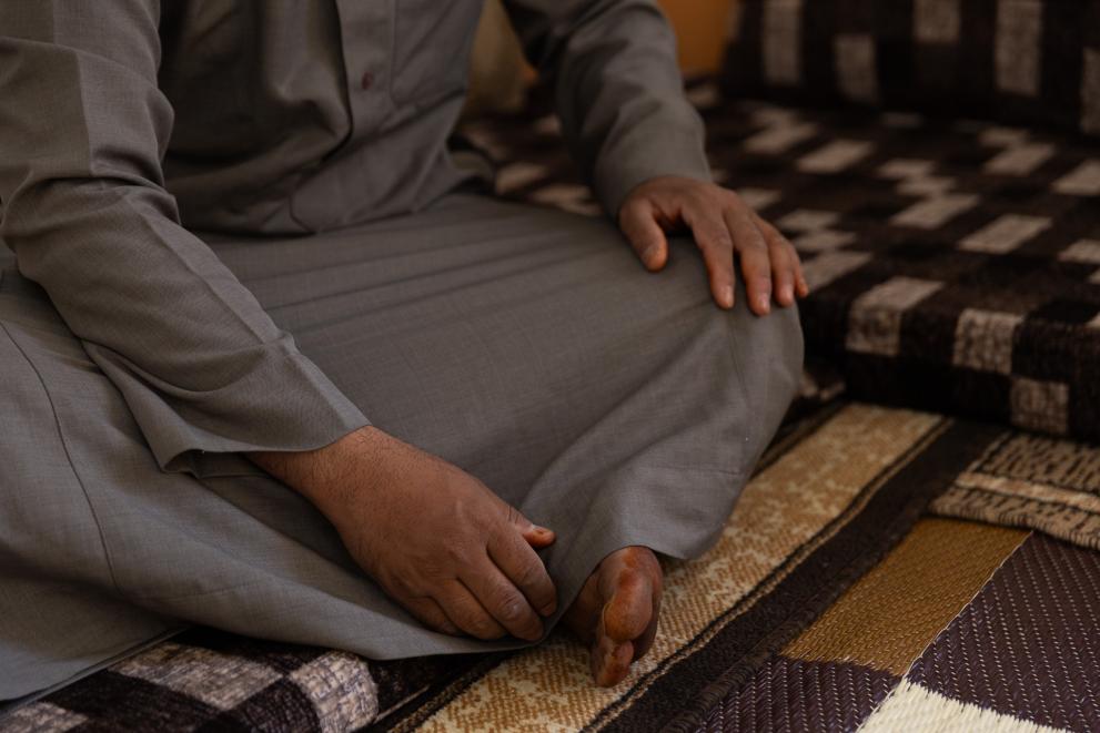 A person sitting on the ground, the hands and legs are visible.